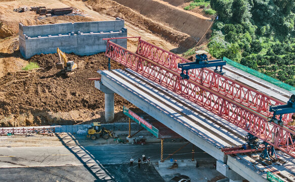 Bridge Construction Site with Red Steel Girders and Heavy Equipment