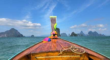 Longtail boat navigating Phangnga Bay's limestone islands, Takua Thung, Thailand.