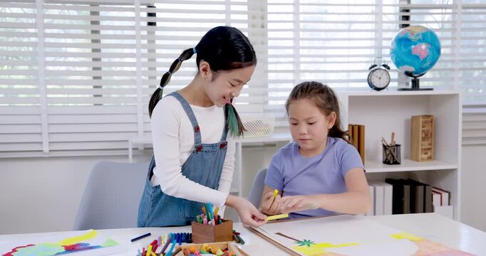 asian girl holding drawing standing beside caucasian girl student concentrating on picture during classroom art activity teamwork creativity friendship learning childhood education study encouragement - Powered by Adobe