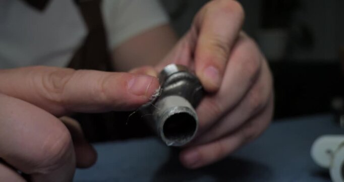 Professional plumber's hands carefully wrapping white ptfe thread seal tape around a water pipe fitting to ensure a watertight connection during plumbing installation or repair work.