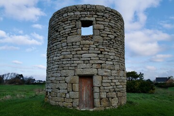 Round stone tower in a green field under blue sky &mdash; rustic rural architecture with copy space