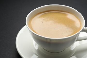 Aromatic coffee in cup on black background, closeup