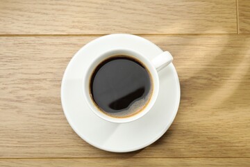 Obraz premium Aromatic coffee in cup on wooden table, top view