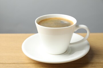 Fototapeta premium Aromatic coffee in cup on wooden table, closeup