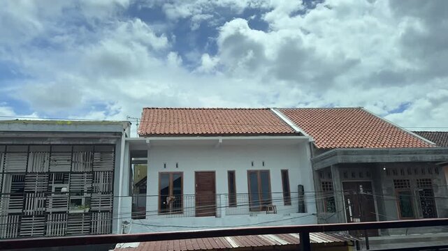 Time lapse of cloudy sky above residential houses on a sunny day with diverse architecture. Time-lapse clouds video