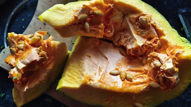 Close-up of Fresh Raw Pumpkin Slices with Seeds on a Wooden Cutting Board