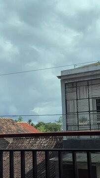 Time lapse Overcast day view from a building balcony featuring an old tiled roof and a modern structured buildings. Vertical Time-lapse clouds video