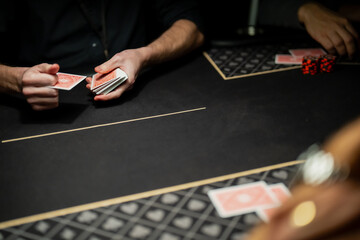 Casino poker dealer hands managing card deck on gaming table surface, illustrating professional dealing technique and operational standards in gambling industry