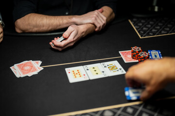 Live casino poker table scene showing dealer and players hands, community cards revealed, and stacked chips during regulated gambling operations