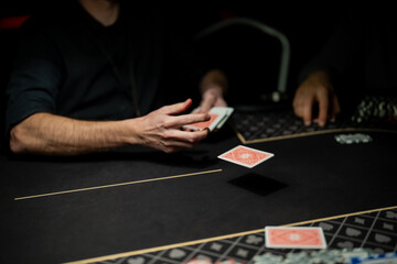 Casino poker dealer releasing a single playing card mid air toward betting area, capturing precise card motion and regulated dealing practice in live gaming