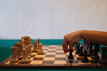 A girl's hand playing chess. The girl is moving the black pawn.
