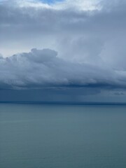 Dramatic cloudy sky over calm sea horizon. Minimal atmospheric seascape with layered storm clouds, soft light and large copy space, suitable for weather, climate, background, nature and emotional