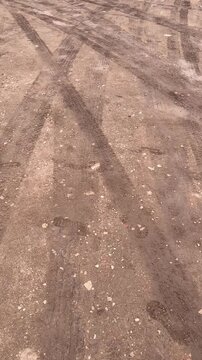 Curving tire marks on wet soil and gravel ground texture