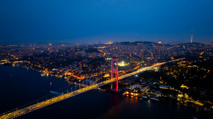Fototapeta premium A breathtaking aerial night view of Istanbul showcasing the illuminated 15 July Martyrs Bridge (Bosphorus Bridge) stretching across the Bosphorus Strait. The city glows.