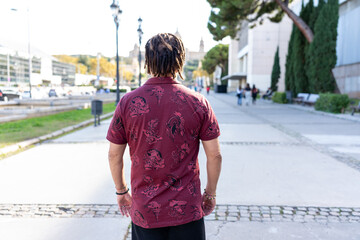 Man with dreadlocks walking outdoors, discovering a city during a sunny day