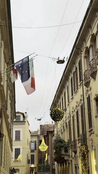 Italian and EU flags are displayed on Montenapoleone Street in Milan, Italy. State Primary School Via della Spiga