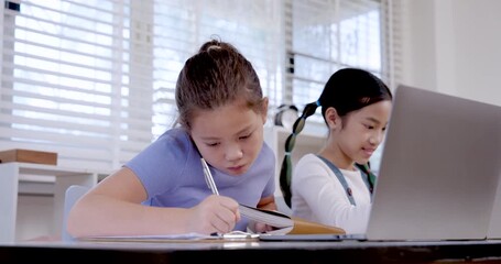 Caucasian preteen girl writing in notebook while asian girl smiling beside laptop during classroom activity representing collaboration teamwork education study digital learning productivity project - Powered by Adobe