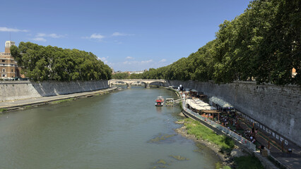 Fototapeta premium Tiber River with Summer Cafés and Tree-Lined Banks in Rome, Italy