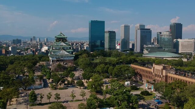 Aerial drone shot moving forward toward Osaka Castle with modern city skyline.