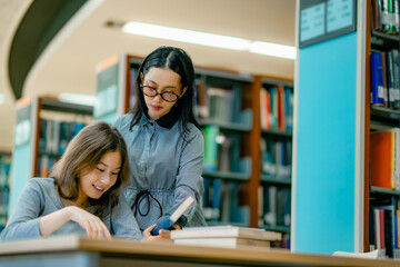 University learners reading research books together at library discussing academic information...