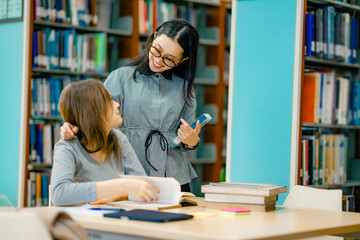 Private tutoring session inside library with tutor guiding student through reading study books showing personalized education support learning progress