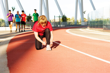 Young woman ties her shoelace on a treadmill