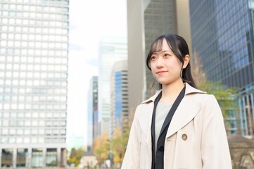 オフィス街で遠くを見つめる20代のビジネスウーマン