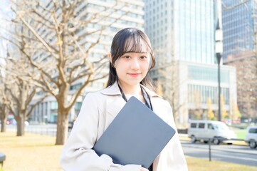 オフィス街でノートパソコンを持つビジネスウーマン