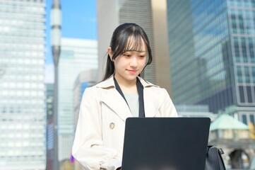 オフィス街でノートパソコンを持つビジネスウーマン
