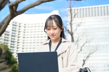 オフィス街でノートパソコンを持つビジネスウーマン