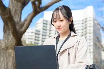 オフィス街でノートパソコンを持つビジネスウーマン