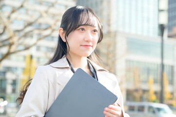 オフィス街でノートパソコンを持つビジネスウーマン