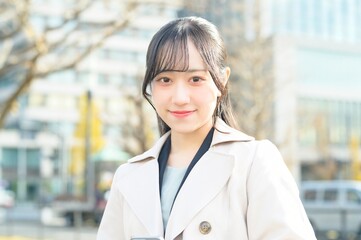 オフィス街でスマホを使用する20代のビジネスウーマン