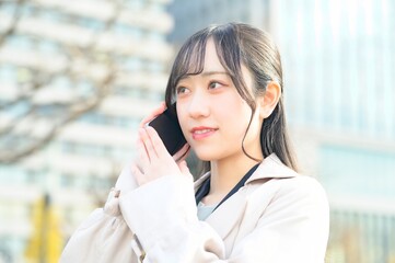 オフィス街でスマホを使用する20代のビジネスウーマン