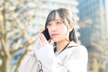 オフィス街でスマホを使用する20代のビジネスウーマン