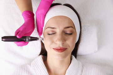 Woman undergoing microneedling procedure in beauty salon, top view