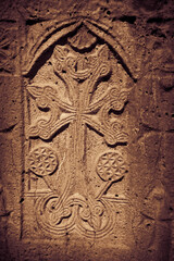 Khachkar - medieval Armenian headstone bearing carved cross, life scenes or decorative interlaces and botanical motifs. Close up sepia toned image