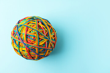 Ball made of many colorful rubber bands on light blue background, top view. Space for text