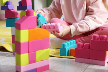 Little girl playing with toys on floor in playroom, closeup