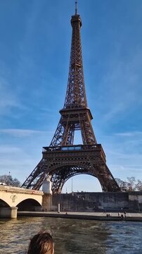 Beautiful woman enjoys a boat cruise along the Seine River in Paris admiring the Eiffel Tower as the boat passes underneath the Pont d'Iena bridge