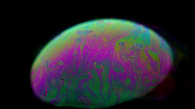 Extreme macro time-lapse footage capturing the dynamic life cycle of a soap bubble. Witness the thin film evolve through stages resembling biological processes: cell division, amoeba movement, or gala