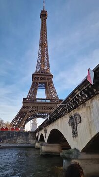 Beautiful woman enjoys a boat cruise along the Seine River in Paris admiring the Eiffel Tower as the boat passes underneath the Pont d'Iena bridge