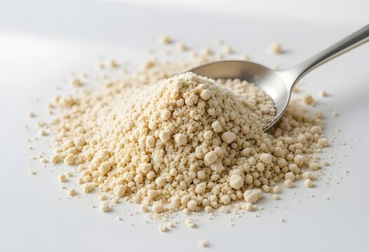 A close-up shot of light beige granular powder with a metallic spoon on a pristine white surface. cbd isolate powder