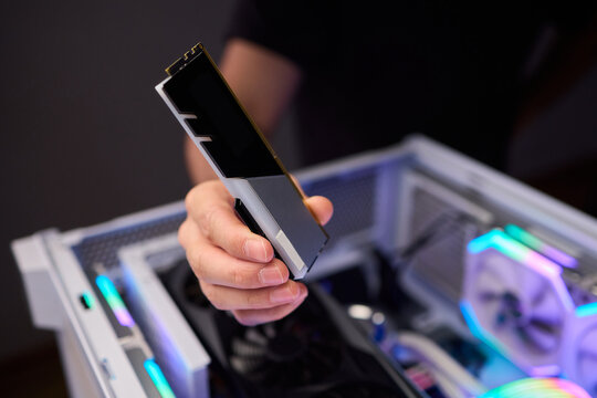 Upgrading computer with RGB lighting, Close up of hardware components during upgrade, Detailed view of installing RAM module into gaming computer with stylish lighting