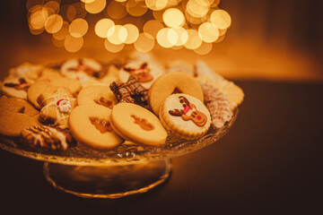 Christmas cookies close up. Christmas cookies on a glass tray. In background Christmas tree. Christmas lights.