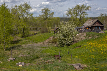 An old village in the countryside, overgrown with trees. Wells with spring water in the old village. Rural landscape in summer. Blooming meadows in the village.