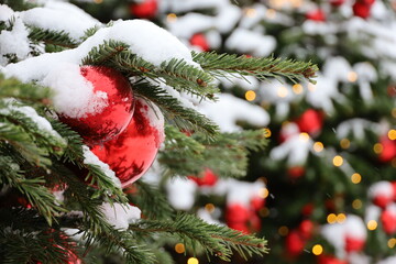Christmas tree with red toy balls and festive illumination, golden lights on background. New Year tree with snow