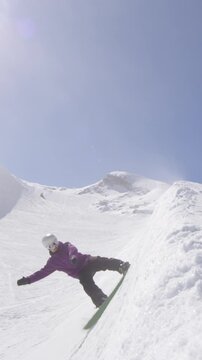 SLOW MOTION: Young pro snowboarder sliding on half pipe wall in sunny snowpark