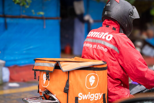Food delivery rider from Swiggy with a zomato bag showing the multi hatting with food technology apps that the gig workers do to ensure sustainable income
