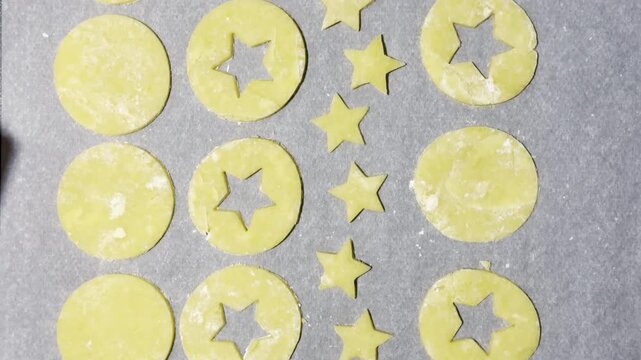 Homemade Alsatian bredele cookie dough cut into star and round shapes on parchment-lined baking tray, lightly floured and ready to bake for Christmas holiday treats
